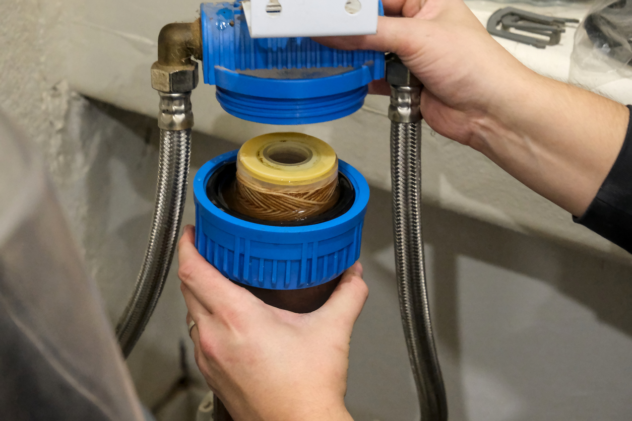 Cheron Olivier | Replacement of a water softener filter cartridge by a technician, in a house.